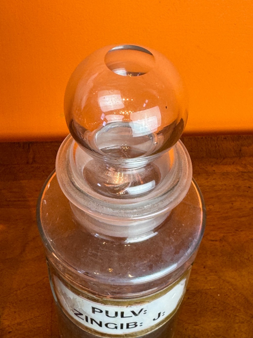 A collection of clear glass antique chemist bottles featuring ground glass stoppers and Latin apothecary labels trimmed in gold. View VII