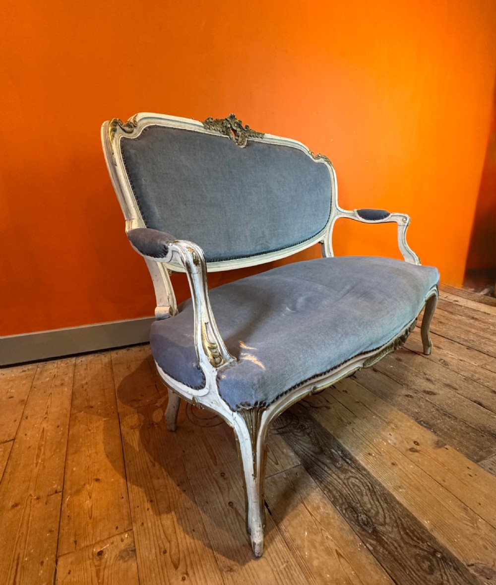 An antique Louis XV style two-seat settee featuring a cream painted and carved wooden frame with gilt accents, cabriole legs, and blue-grey fabric upholstery. View III