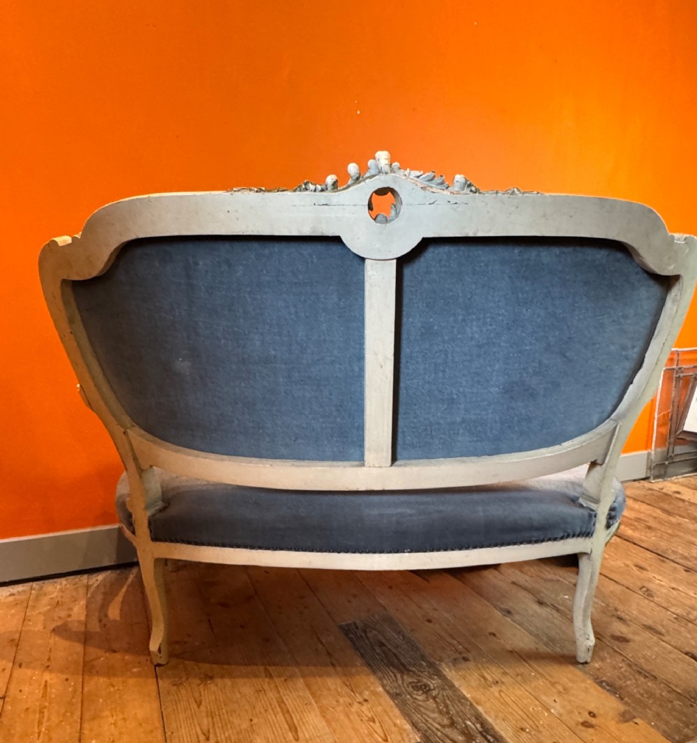 An antique Louis XV style two-seat settee featuring a cream painted and carved wooden frame with gilt accents, cabriole legs, and blue-grey fabric upholstery. View IV