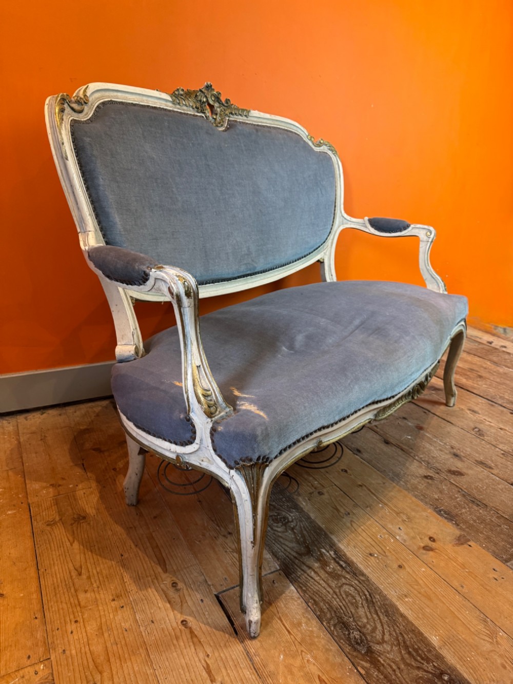 An antique Louis XV style two-seat settee featuring a cream painted and carved wooden frame with gilt accents, cabriole legs, and blue-grey fabric upholstery. View V