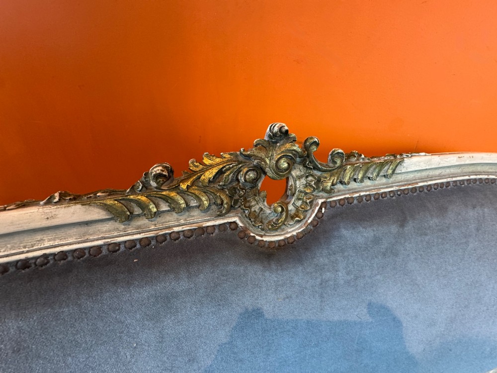 An antique Louis XV style two-seat settee featuring a cream painted and carved wooden frame with gilt accents, cabriole legs, and blue-grey fabric upholstery. View VI