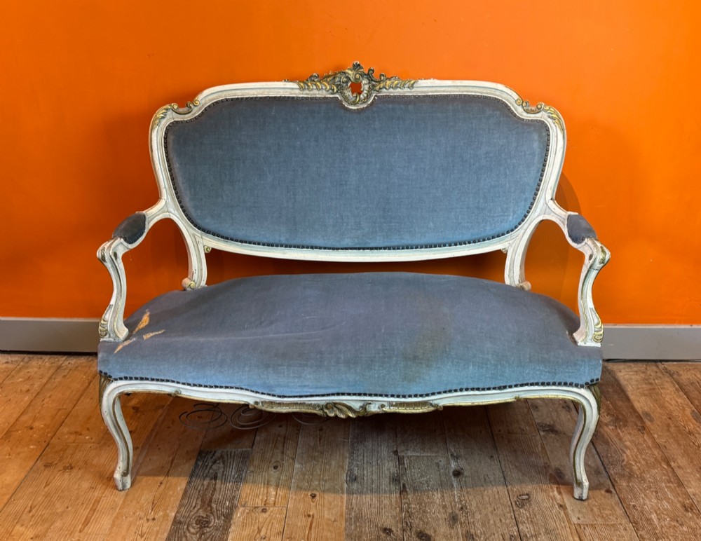 An antique Louis XV style two-seat settee featuring a cream painted and carved wooden frame with gilt accents, cabriole legs, and blue-grey fabric upholstery. View VIII