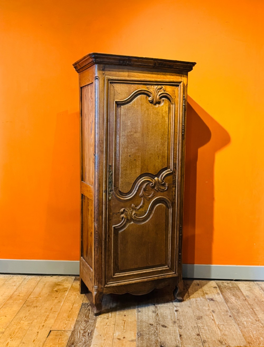 A 19th-century French oak bonnetiere featuring a single door with Louis XV style carved foliate mouldings, long iron hinges, and cabriole feet. View VII