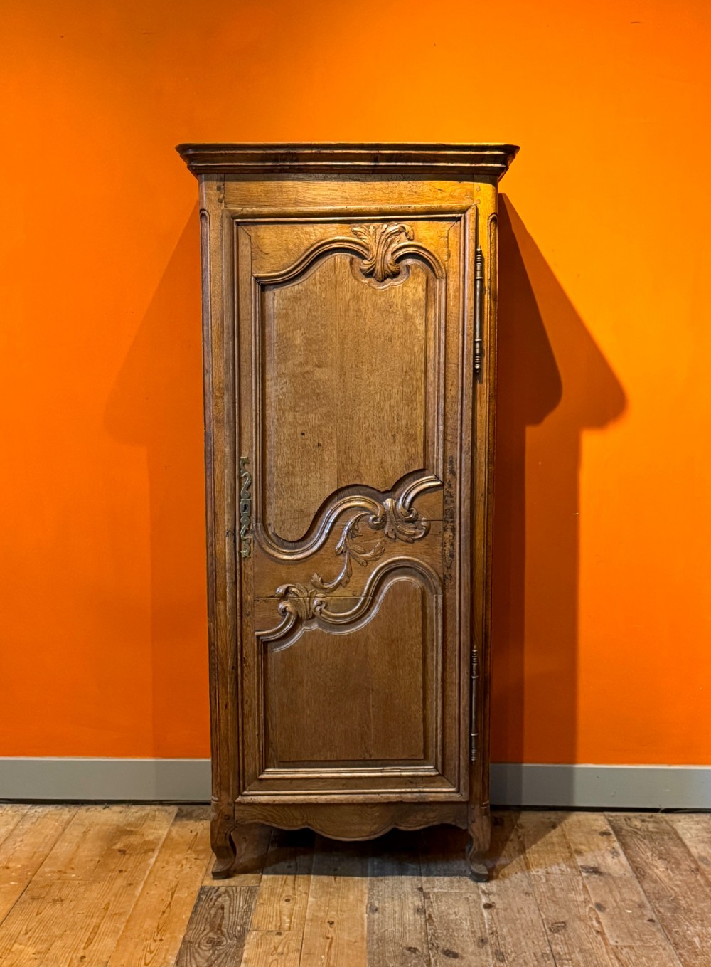 A 19th-century French oak bonnetiere featuring a single door with Louis XV style carved foliate mouldings, long iron hinges, and cabriole feet. View VIII