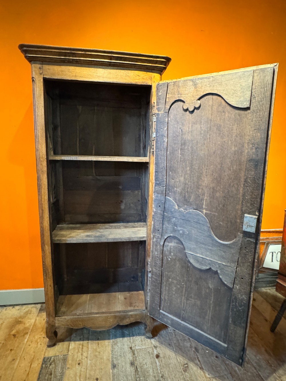 A 19th-century French oak bonnetiere featuring a single door with Louis XV style carved foliate mouldings, long iron hinges, and cabriole feet. View X