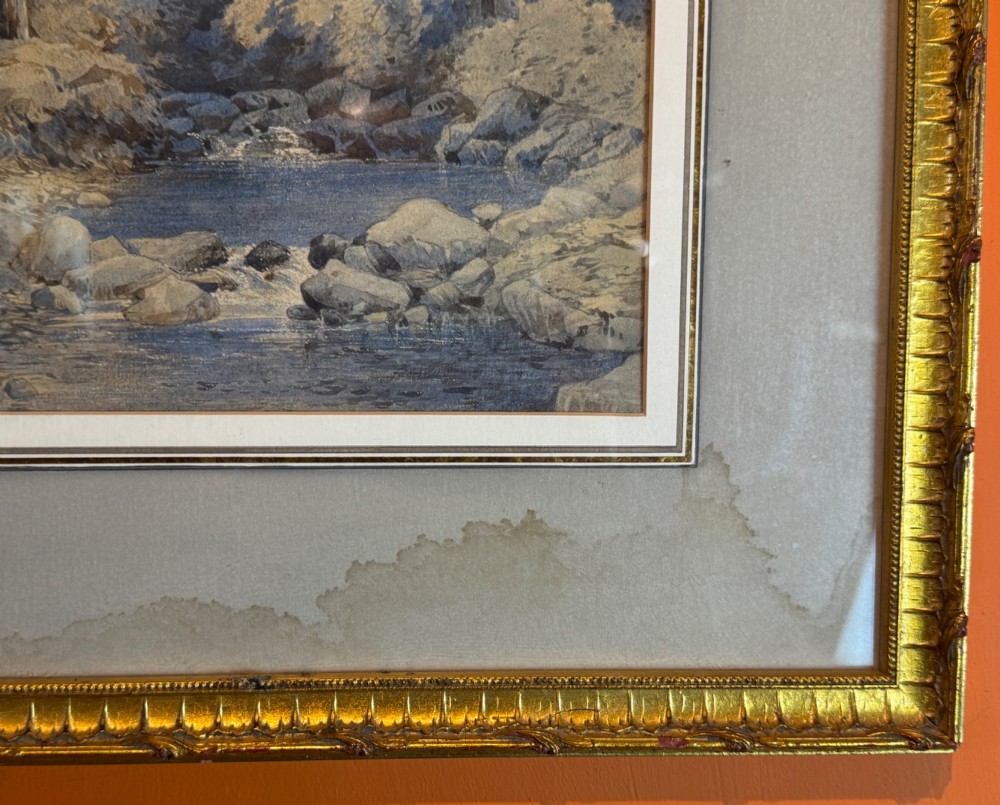 Framed landscape watercolour depicting figures beside a river with trees, presented in a cloth mount and a molded gilt frame. View V