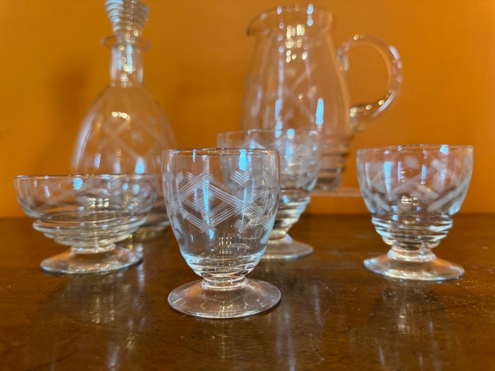 A 34-piece clear glass drinkware suite featuring engraved geometric motifs, including a stoppered decanter, water pitcher, stemware, and dessert bowls. View II