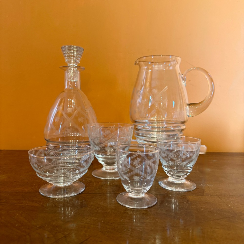A 34-piece clear glass drinkware suite featuring engraved geometric motifs, including a stoppered decanter, water pitcher, stemware, and dessert bowls. View III