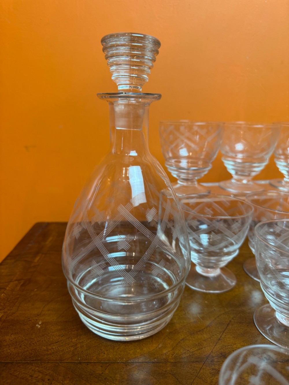 A 34-piece clear glass drinkware suite featuring engraved geometric motifs, including a stoppered decanter, water pitcher, stemware, and dessert bowls. View VI