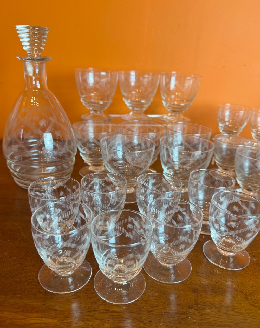 A 34-piece clear glass drinkware suite featuring engraved geometric motifs, including a stoppered decanter, water pitcher, stemware, and dessert bowls. View IX