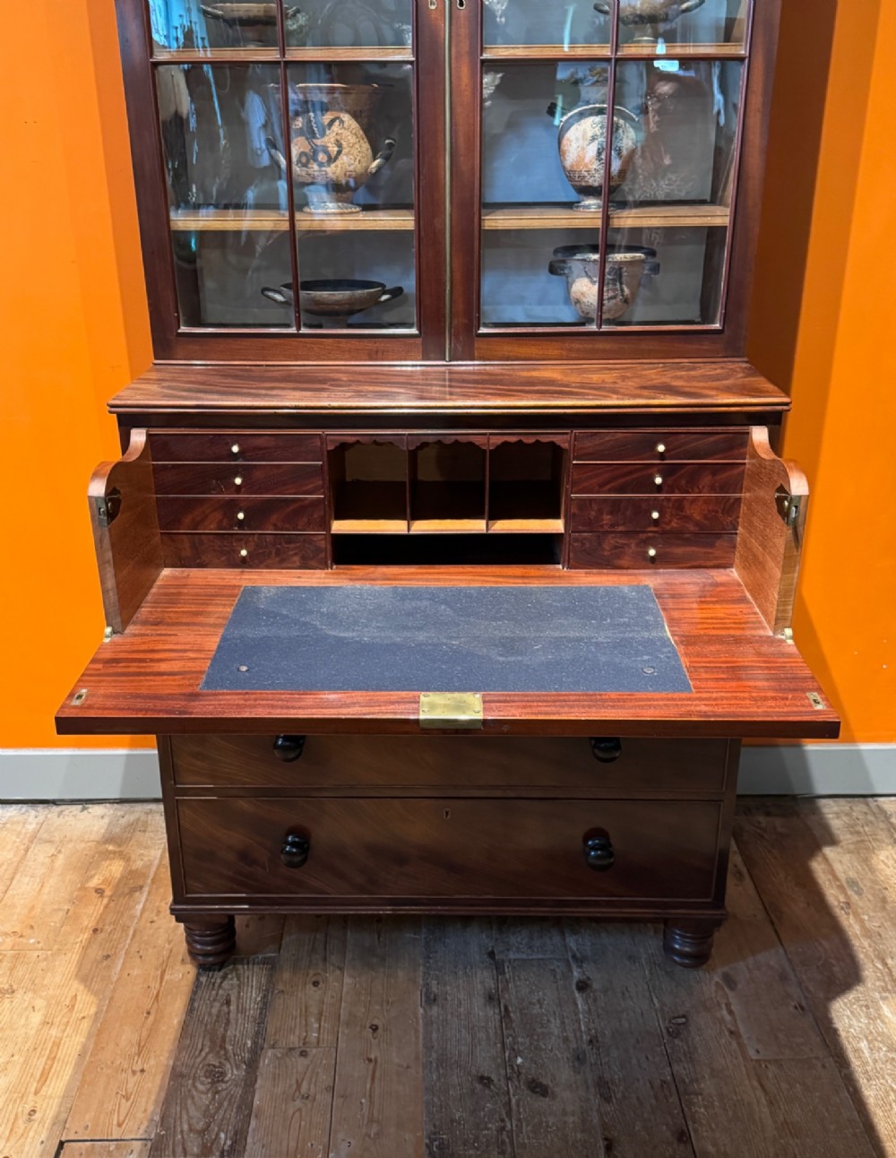 An antique Regency mahogany secretaire bookcase featuring upper Gothic astragal glazed doors over a lower chest of drawers on turned feet. View III