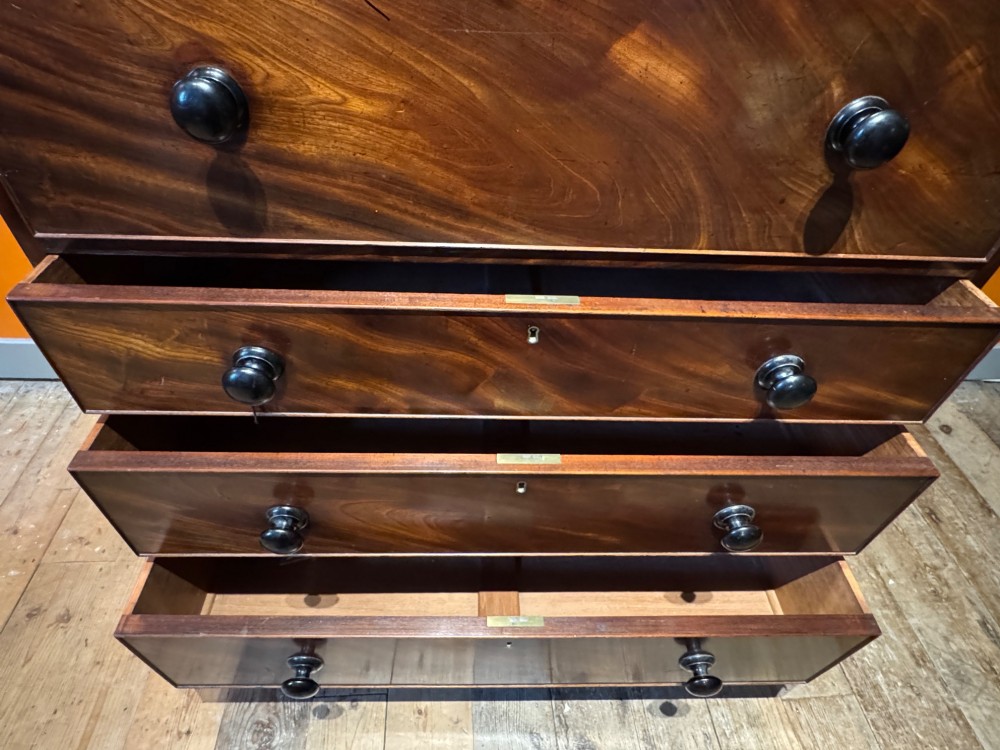 An antique Regency mahogany secretaire bookcase featuring upper Gothic astragal glazed doors over a lower chest of drawers on turned feet. View IV