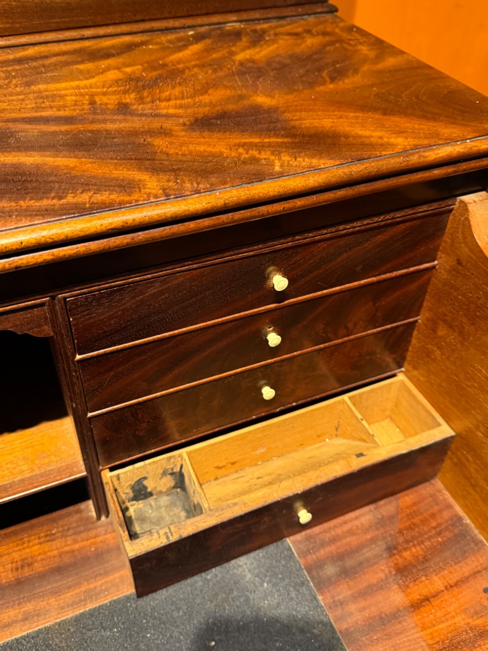 An antique Regency mahogany secretaire bookcase featuring upper Gothic astragal glazed doors over a lower chest of drawers on turned feet. View VIII