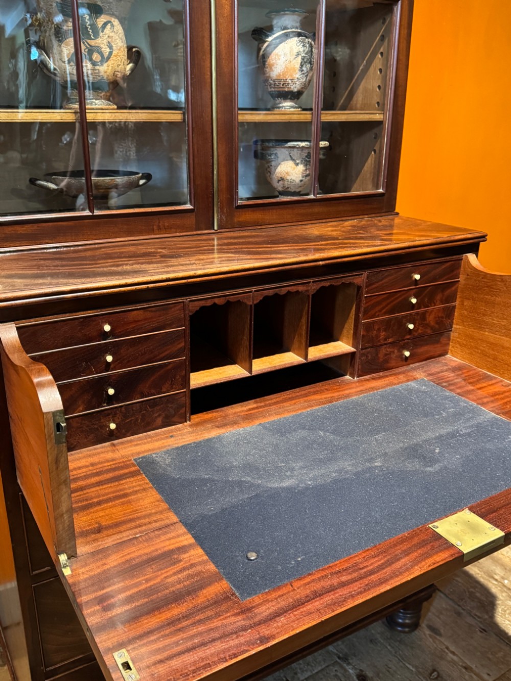 An antique Regency mahogany secretaire bookcase featuring upper Gothic astragal glazed doors over a lower chest of drawers on turned feet. View IX