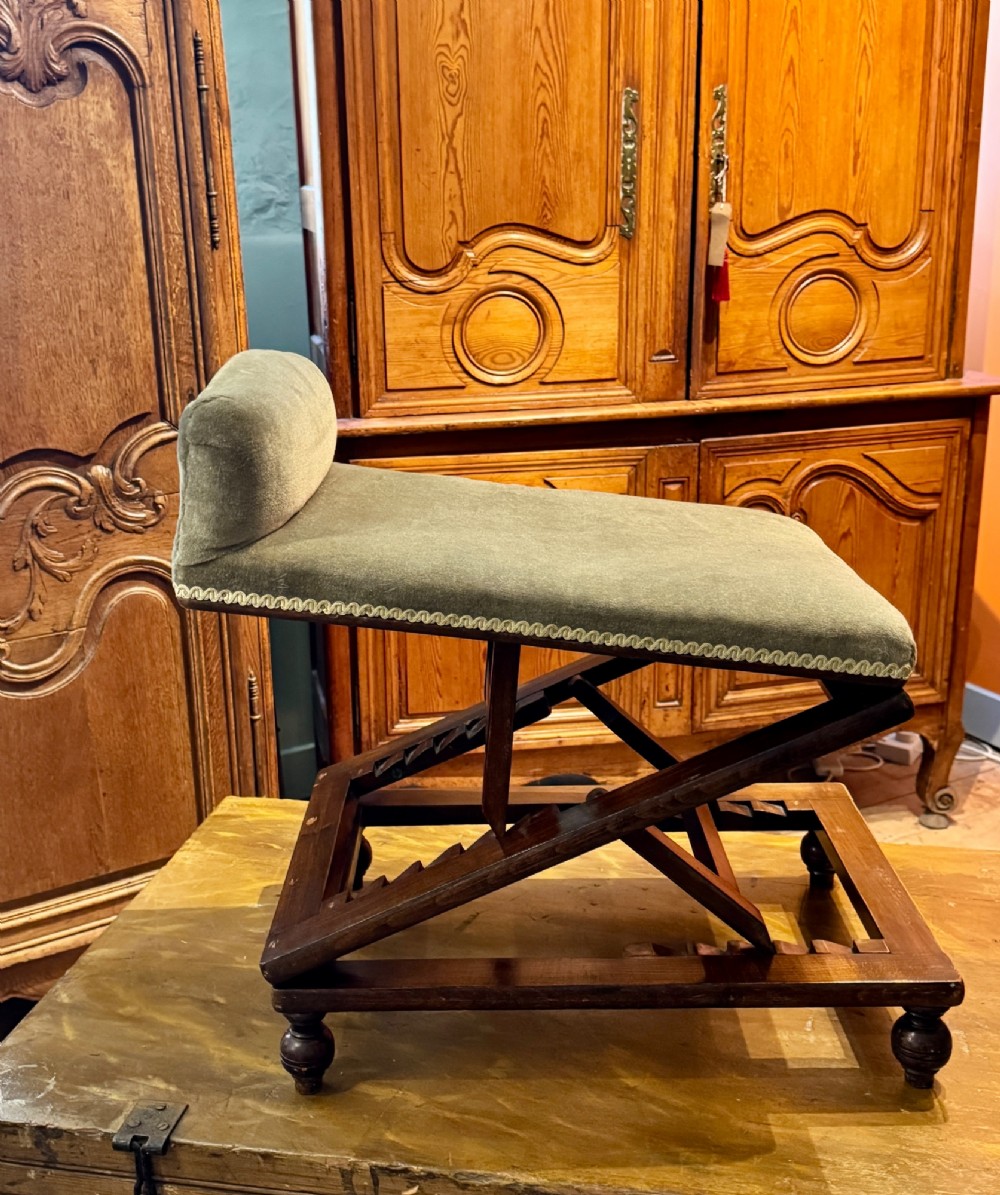 An antique Victorian metamorphic gout stool with a dark stained beech ratchet frame and an inclined green velvet upholstered cushion.