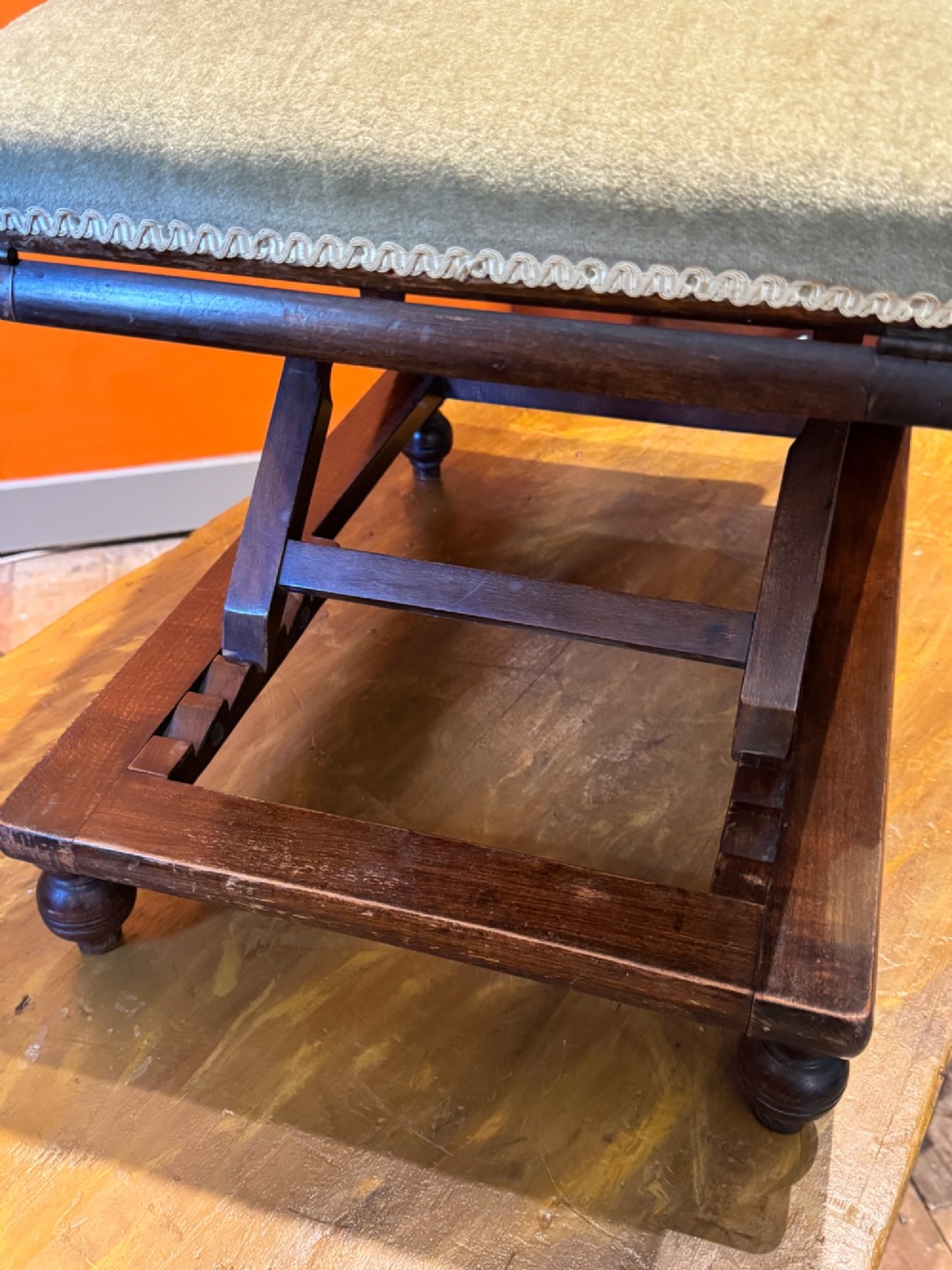 An antique Victorian metamorphic gout stool with a dark stained beech ratchet frame and an inclined green velvet upholstered cushion. View VII