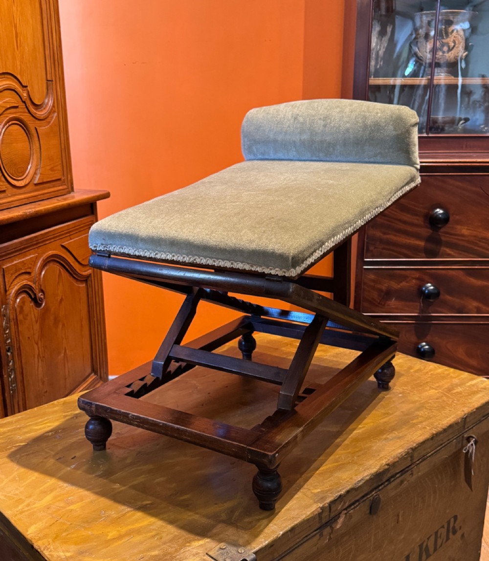 An antique Victorian metamorphic gout stool with a dark stained beech ratchet frame and an inclined green velvet upholstered cushion. View IX