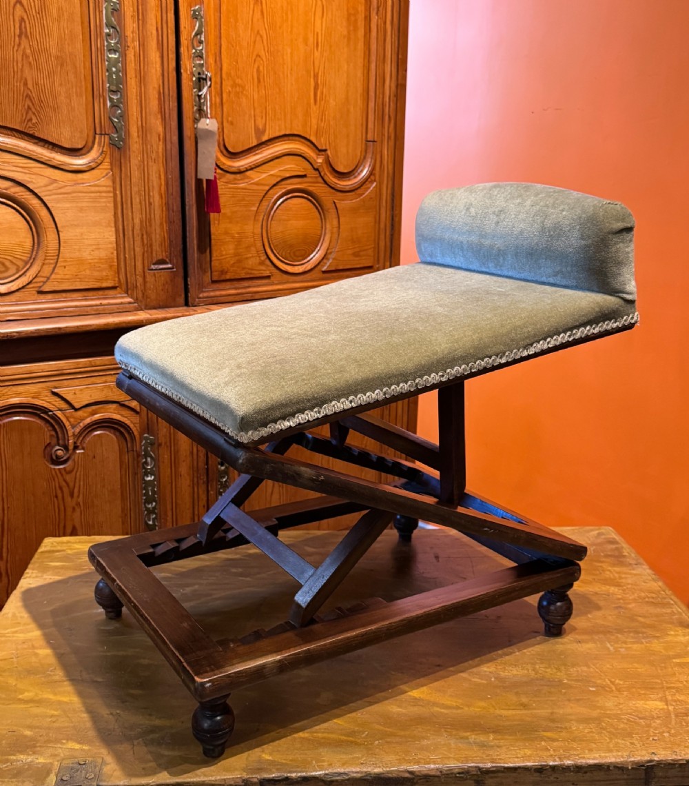 An antique Victorian metamorphic gout stool with a dark stained beech ratchet frame and an inclined green velvet upholstered cushion. View X