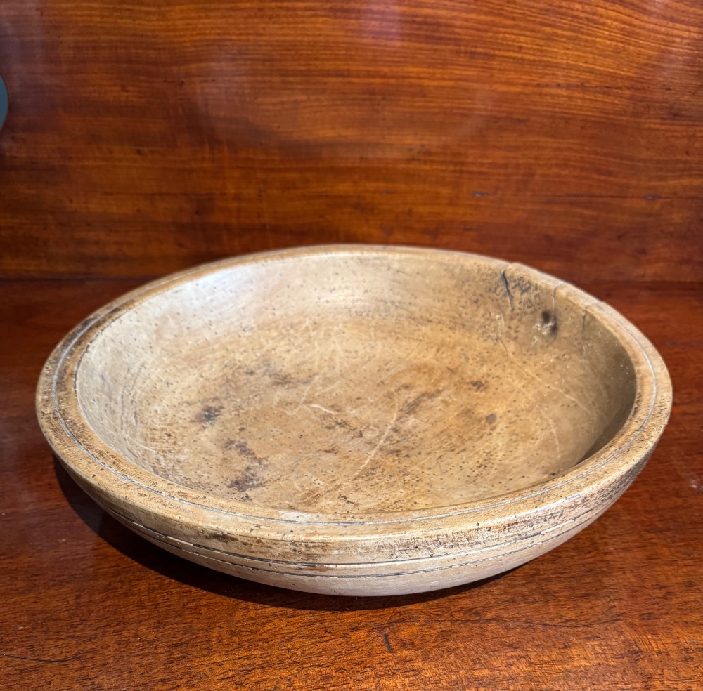 A shallow 19th-century French hand-turned sycamore dairy bowl featuring incised concentric rim lines and natural wood patination.