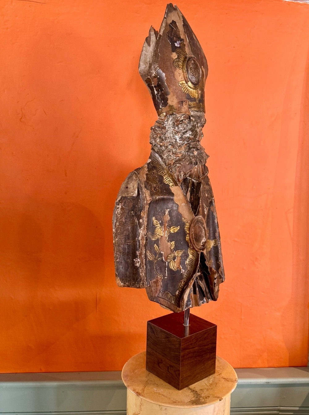 An eighteenth-century carved gilt-wood bust of a bearded bishop wearing a mitre, showing distressed gilding and mounted on a dark wooden block base. View IV