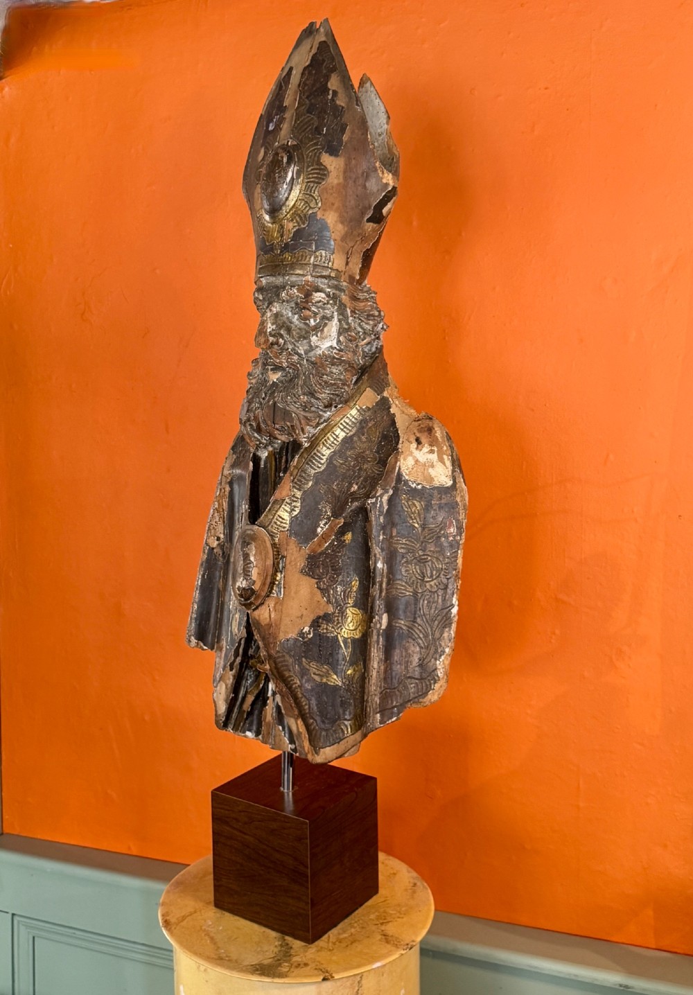 An eighteenth-century carved gilt-wood bust of a bearded bishop wearing a mitre, showing distressed gilding and mounted on a dark wooden block base. View V