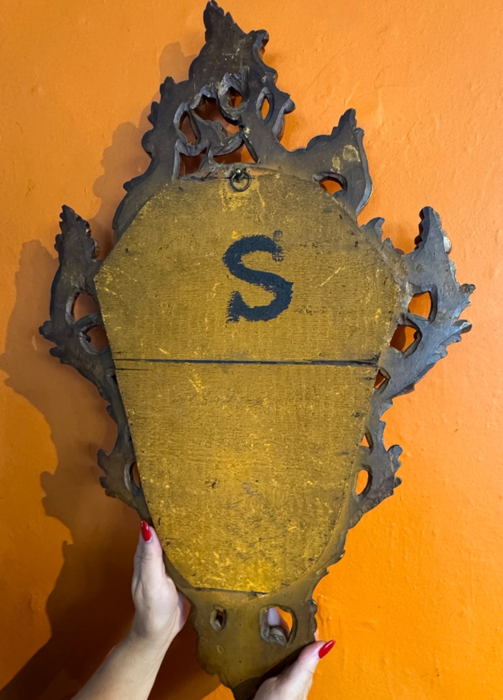 An Italian Rococo carved giltwood wall mirror with an ornate C-scroll frame and an engraved mirror plate displaying a musical instrument motif. View II