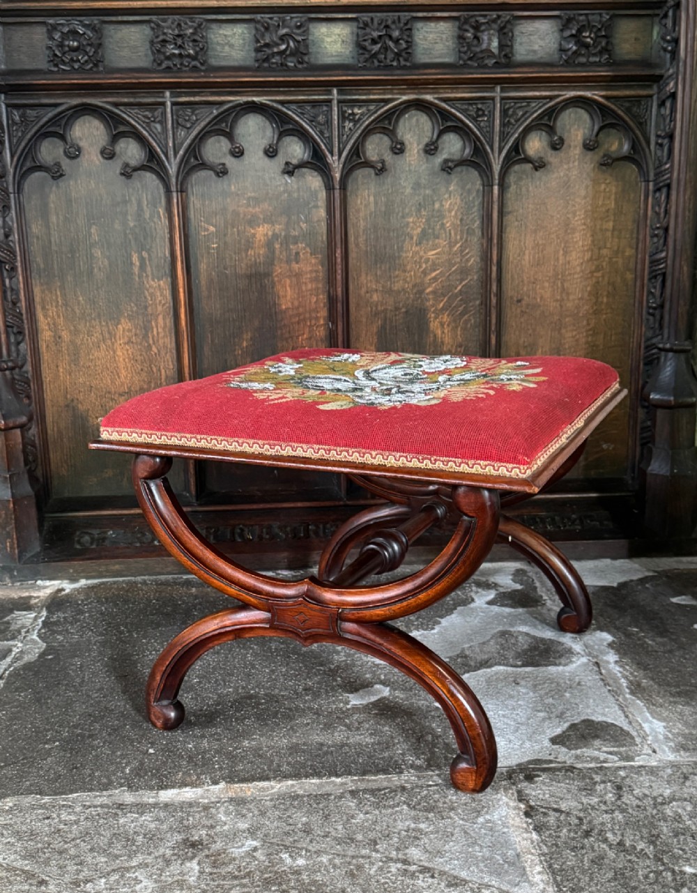 A Victorian walnut stool featuring curved X-frame legs, a turned central stretcher, and a red textile seat embellished with floral glass beadwork.