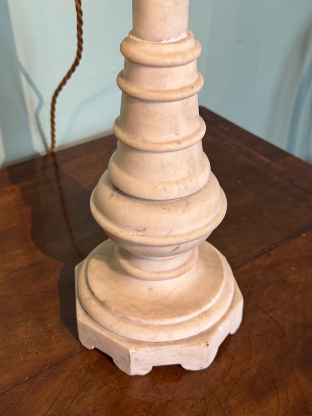 A pair of turned off-white marble table lamps featuring cylindrical baluster shafts, stepped circular bases, and cream pleated fabric shades. View IV