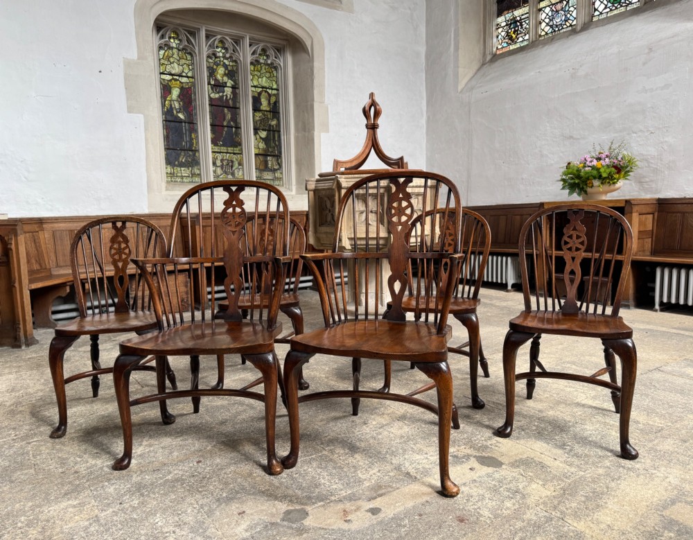 A set of six antique ash and beech Windsor chairs featuring arched backs with wheelback splats, shaped solid seats, and front cabriole legs.