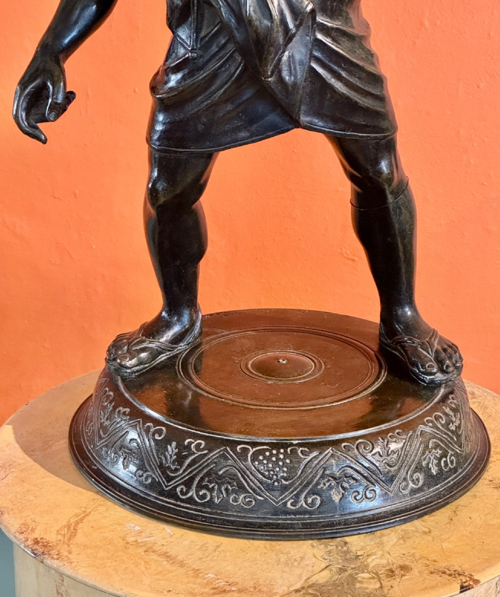 A dark patinated bronze sculptural table lamp depicting the classical figure Silenus holding a coiled serpent, set upon a carved circular base. View III