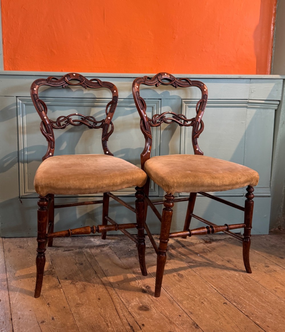 A pair of Victorian dark wood bedroom chairs with pierced scroll carved backrests, dot inlay, turned legs, and velvet seats. View V