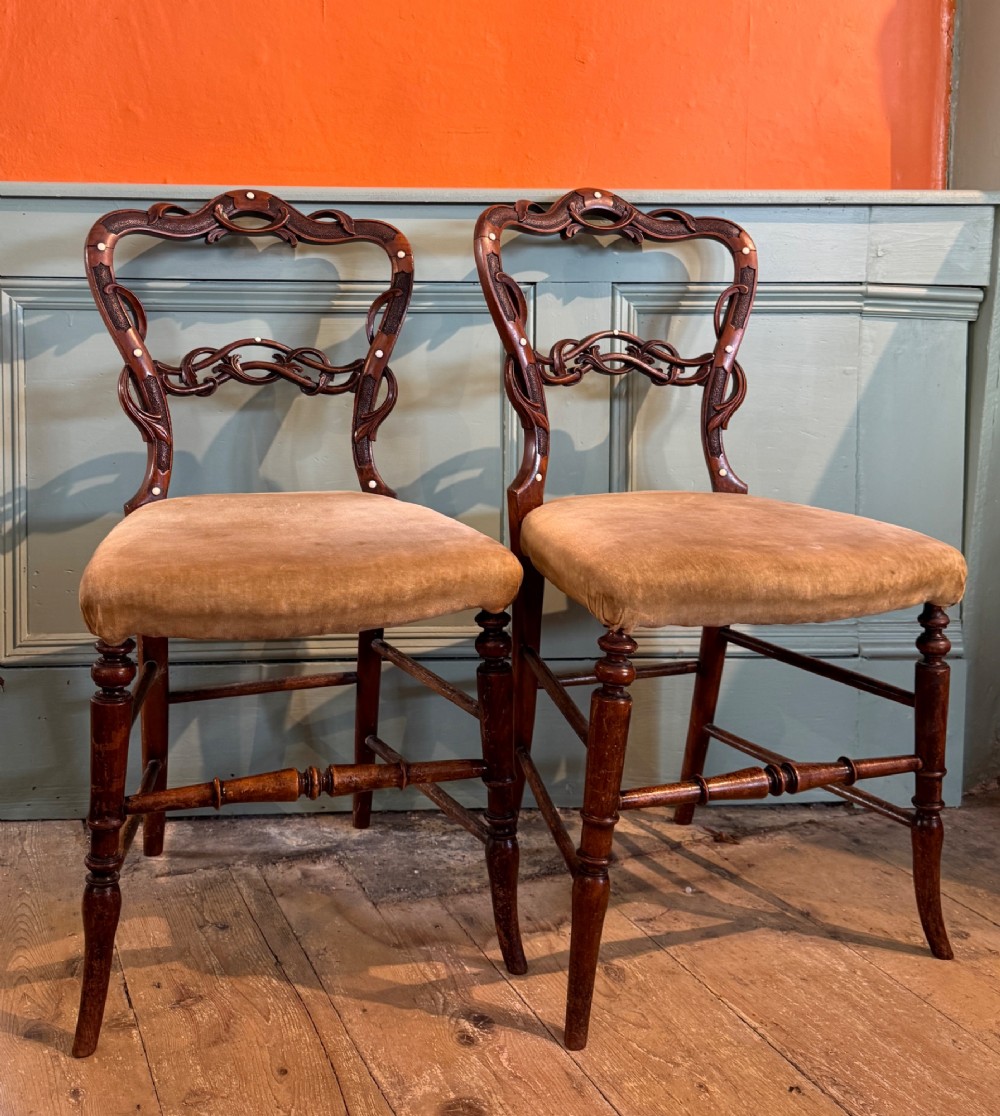 A pair of Victorian dark wood bedroom chairs with pierced scroll carved backrests, dot inlay, turned legs, and velvet seats. View VI