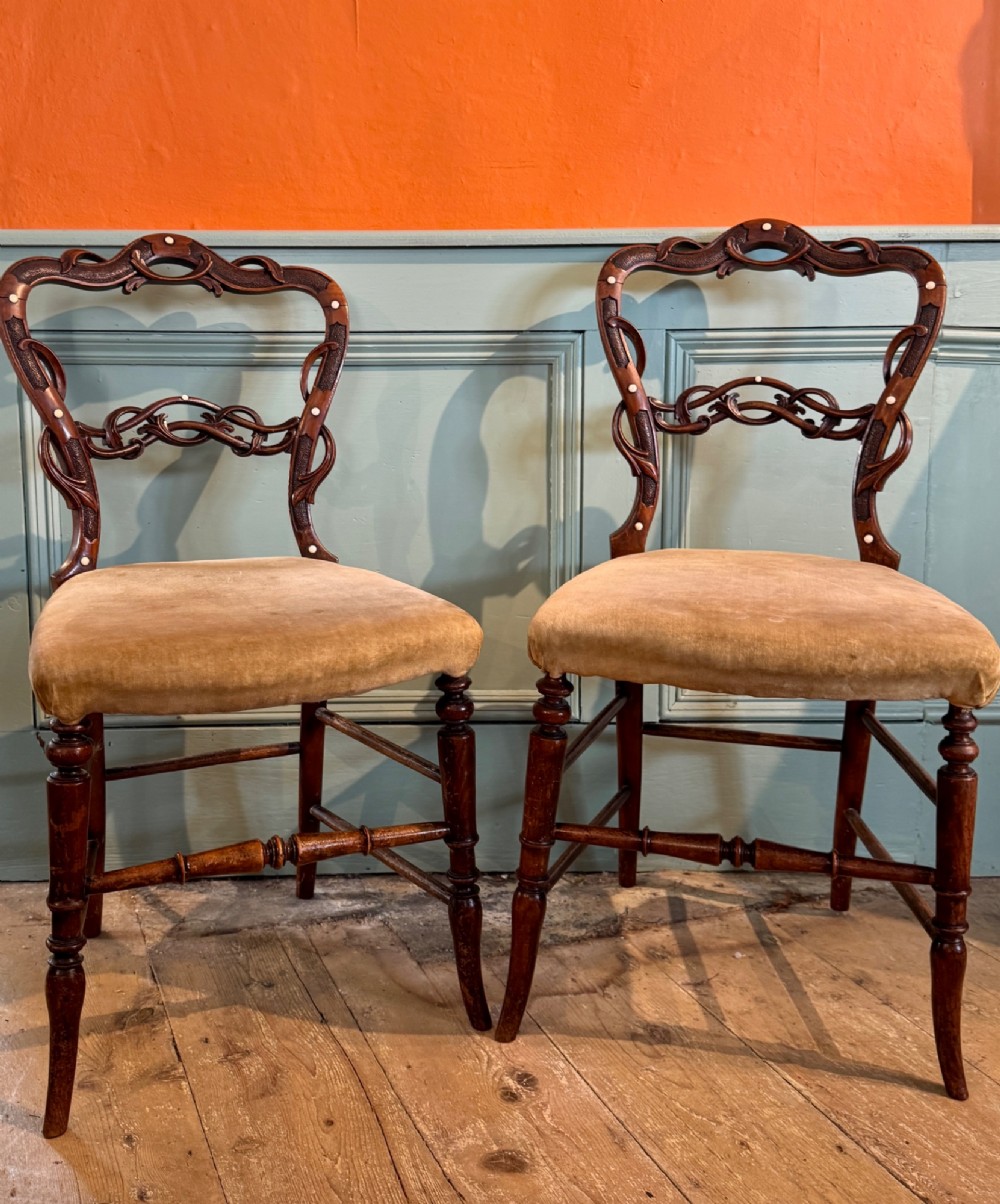 A pair of Victorian dark wood bedroom chairs with pierced scroll carved backrests, dot inlay, turned legs, and velvet seats. View VII