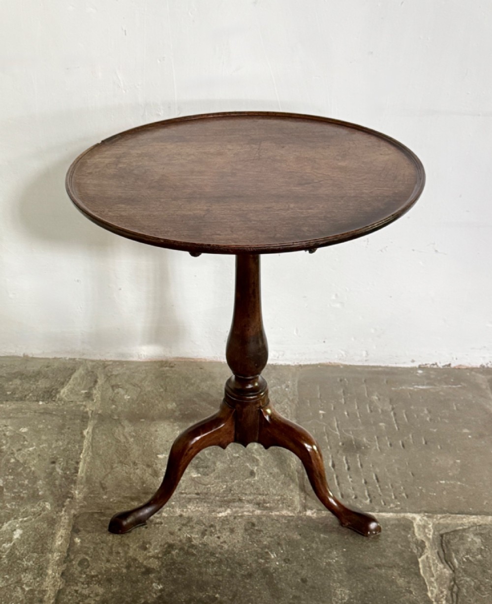 A Georgian mahogany tilt-top tripod table featuring a circular dished top supported by a turned pedestal stem and three cabriole legs.