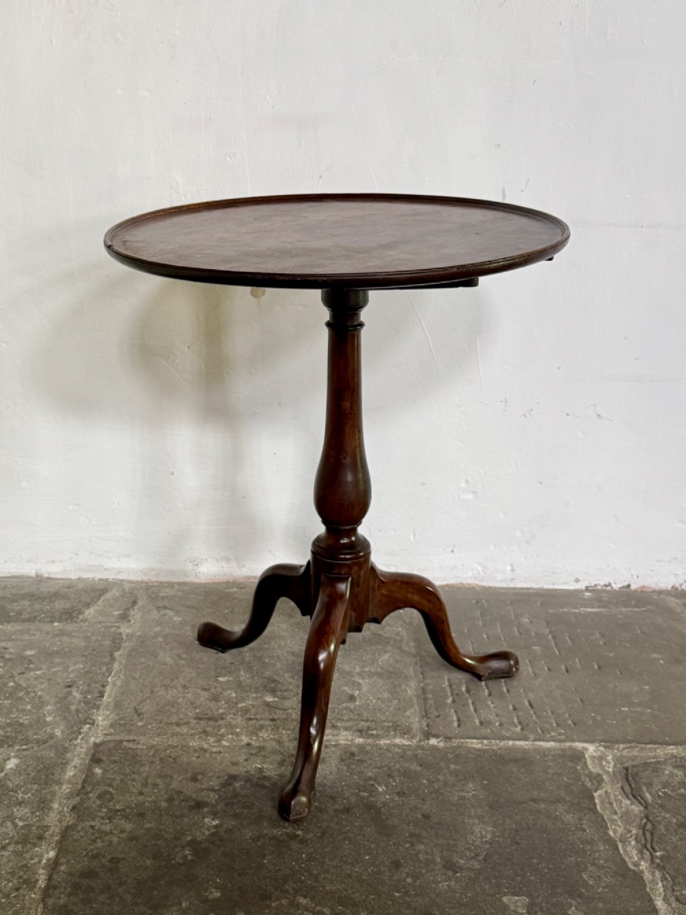 A Georgian mahogany tilt-top tripod table featuring a circular dished top supported by a turned pedestal stem and three cabriole legs. View II