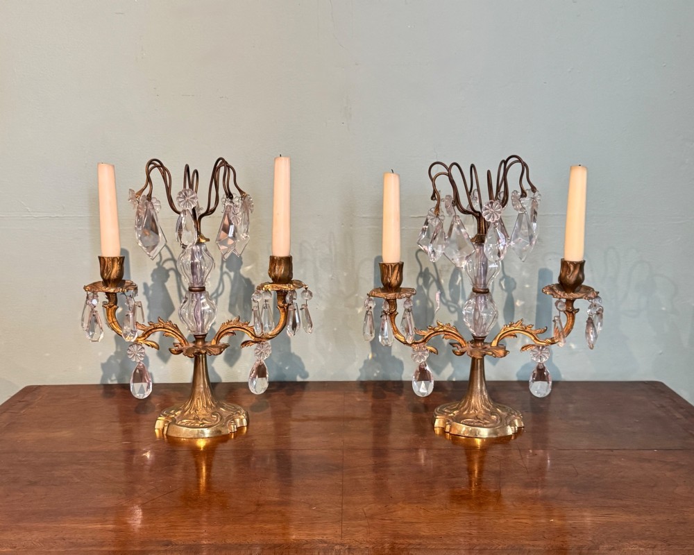 A pair of French gilt-brass two-arm candlestick lustres featuring central crystal elements and hanging cut-crystal drop prisms. View II