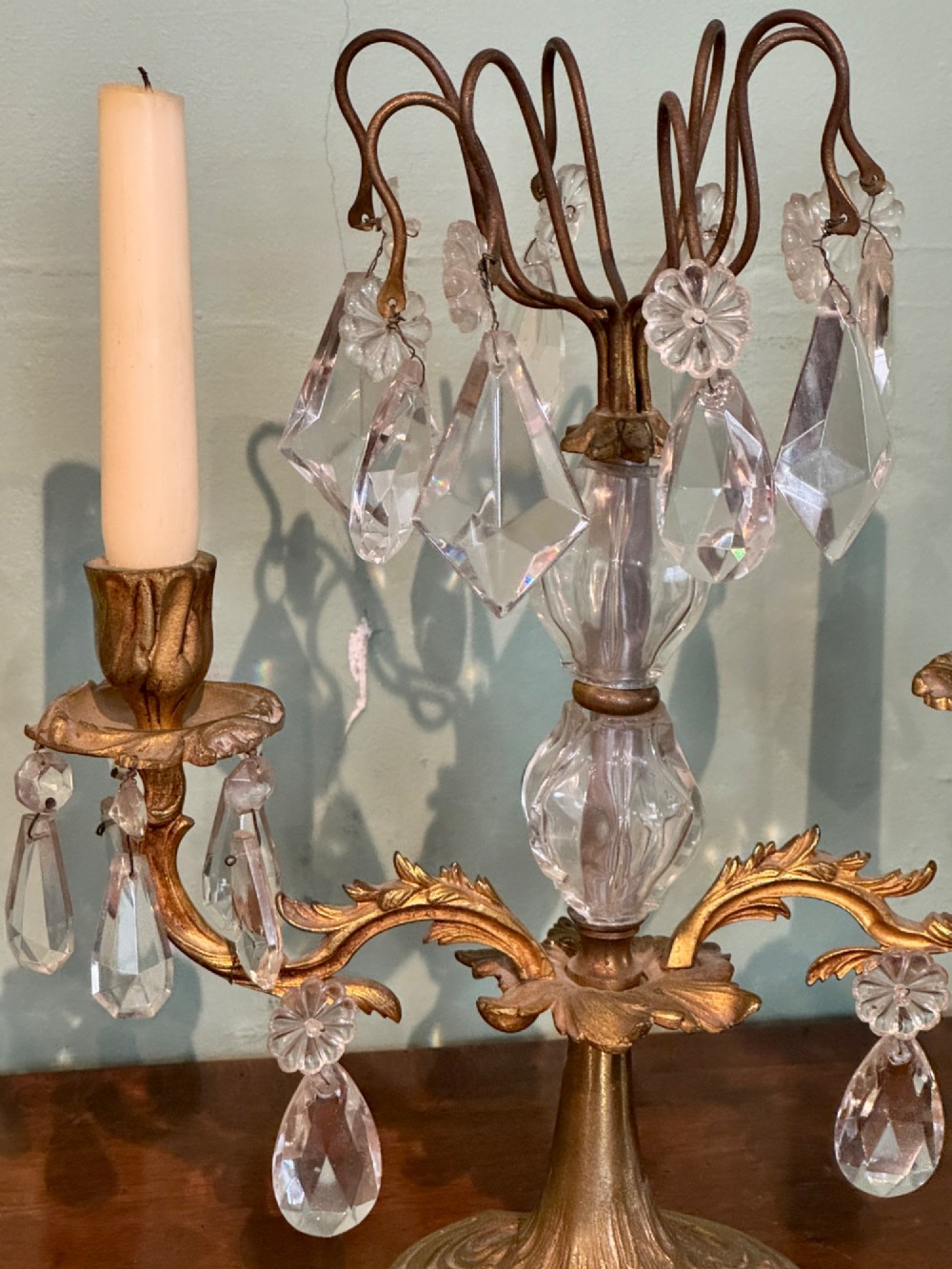 A pair of French gilt-brass two-arm candlestick lustres featuring central crystal elements and hanging cut-crystal drop prisms. View V