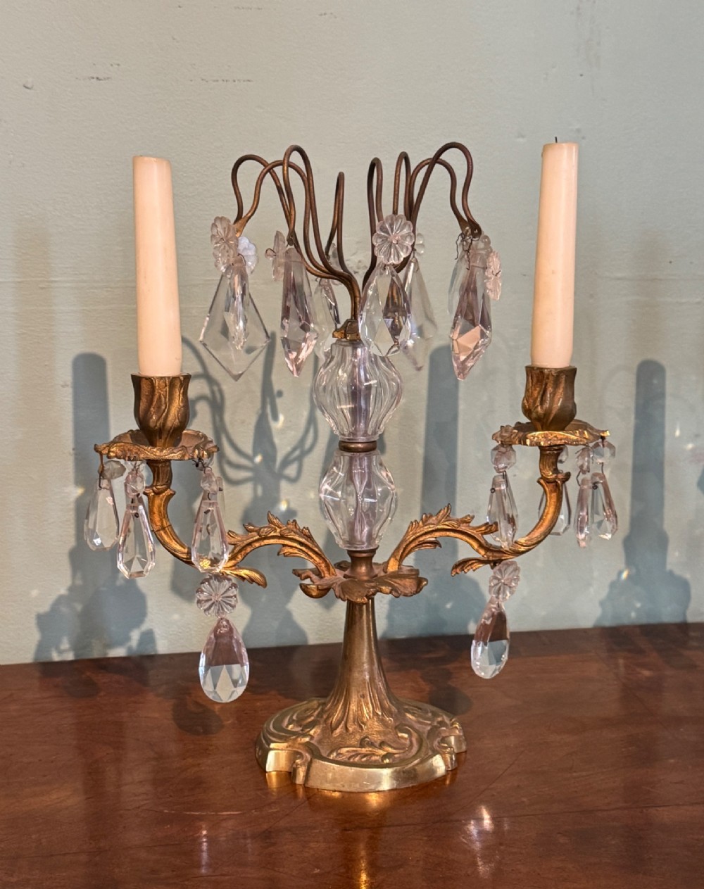 A pair of French gilt-brass two-arm candlestick lustres featuring central crystal elements and hanging cut-crystal drop prisms. View VI