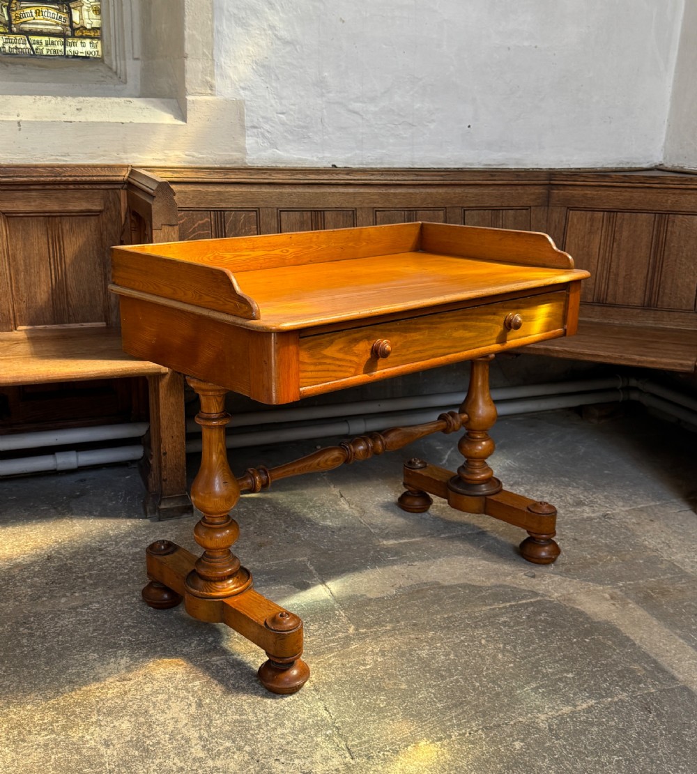 A Victorian pitch pine washstand featuring a raised gallery splashback, a single wide drawer with wooden knobs, and turned trestle legs connected by a stretcher. View II