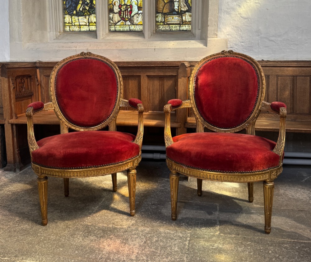 A pair of 19th-century Louis XVI style giltwood armchairs featuring crimson red velvet upholstery and carved medallion backs. View III