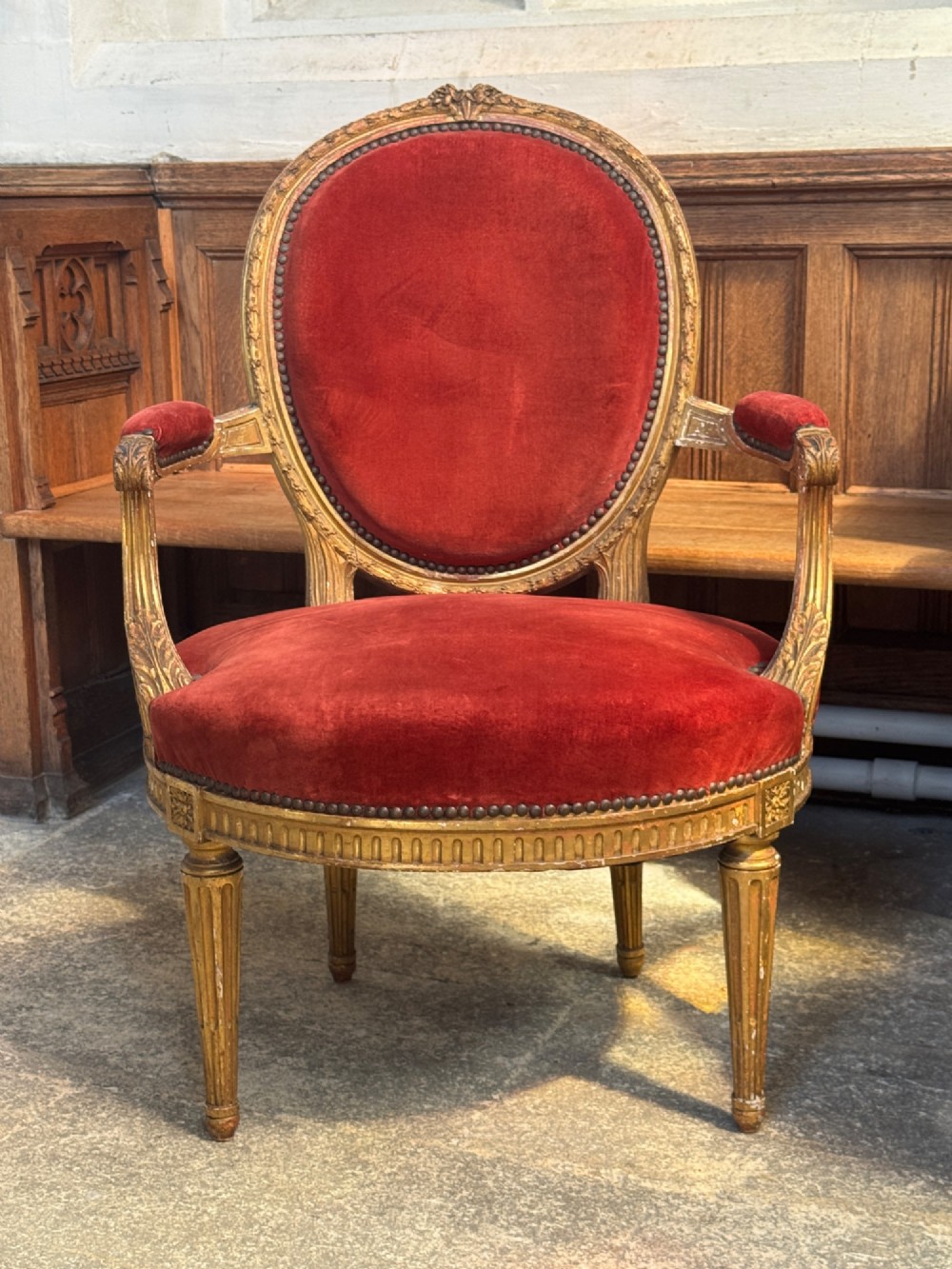 A pair of 19th-century Louis XVI style giltwood armchairs featuring crimson red velvet upholstery and carved medallion backs. View IV