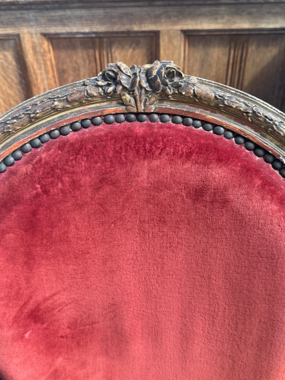 A pair of 19th-century Louis XVI style giltwood armchairs featuring crimson red velvet upholstery and carved medallion backs. View V