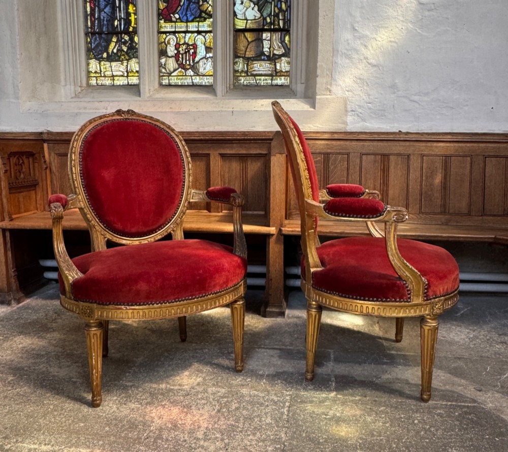 A pair of 19th-century Louis XVI style giltwood armchairs featuring crimson red velvet upholstery and carved medallion backs. View VII