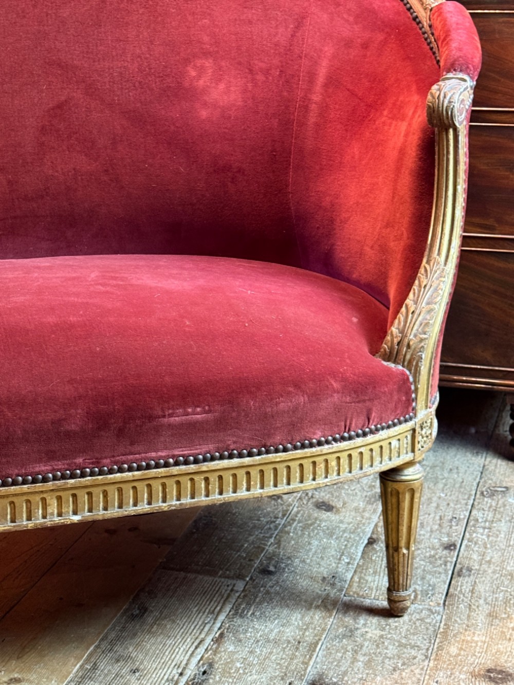 An antique French Louis XVI style two-seat corbeille sofa featuring a carved giltwood frame and deep crimson red velvet upholstery. View V