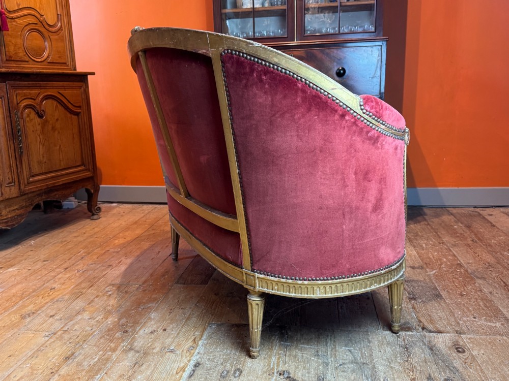 An antique French Louis XVI style two-seat corbeille sofa featuring a carved giltwood frame and deep crimson red velvet upholstery. View VII