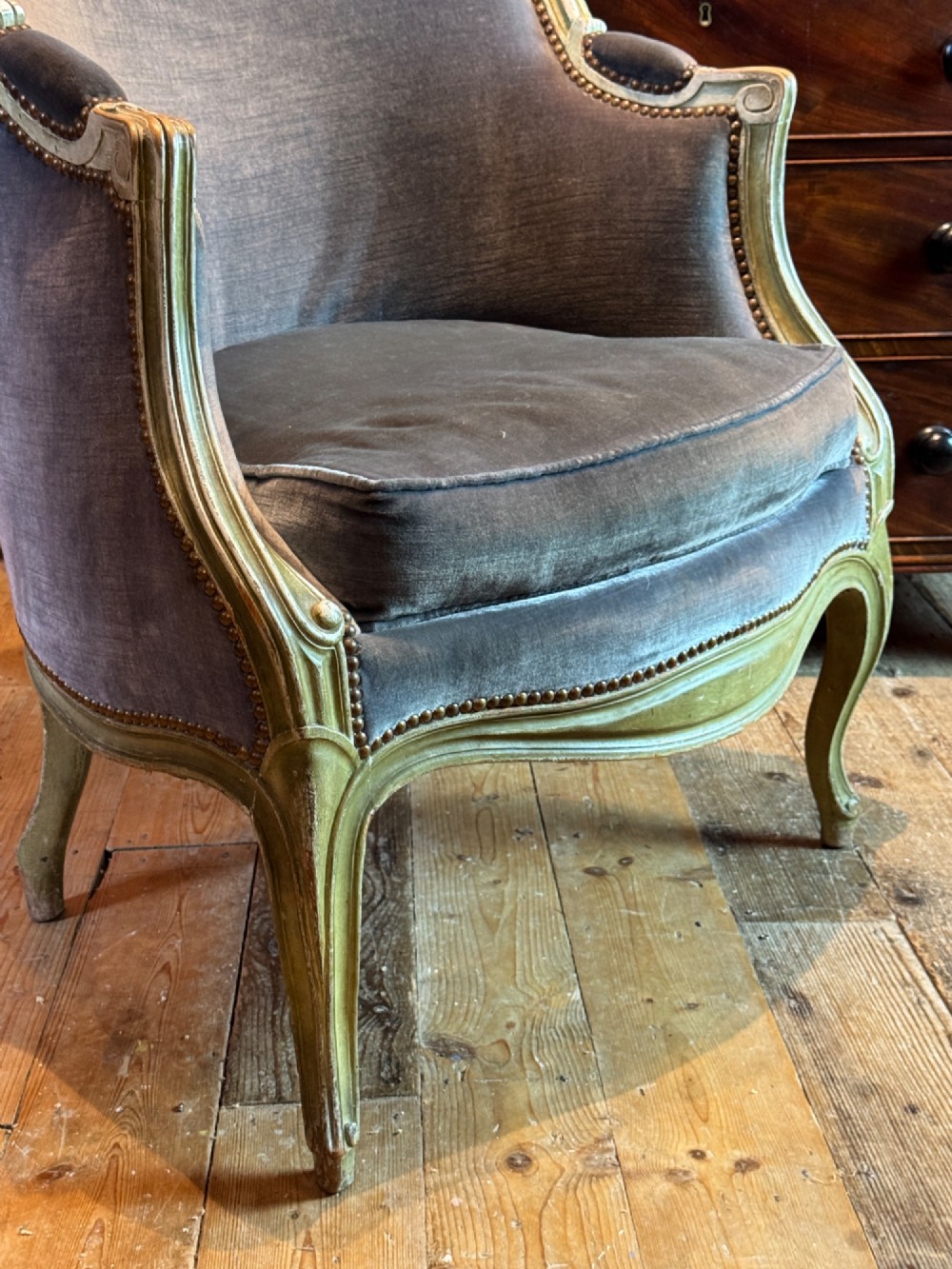 An antique Louis XV style tub bergere armchair upholstered in slate grey velvet with a carved distressed green wooden frame and cabriole legs. View IV