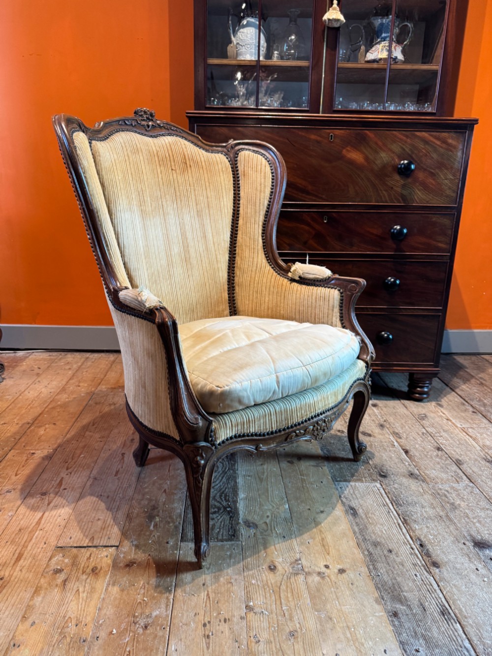A Louis XV style bergere armchair featuring a carved dark wooden frame, enclosed upholstered arms, beige fabric, and cabriole legs. View II