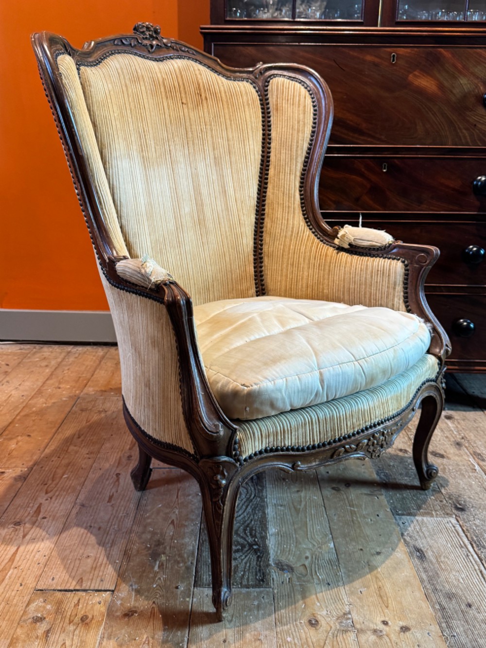 A Louis XV style bergere armchair featuring a carved dark wooden frame, enclosed upholstered arms, beige fabric, and cabriole legs. View III