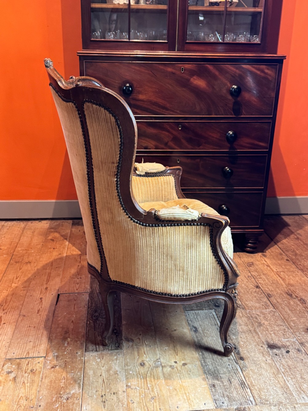 A Louis XV style bergere armchair featuring a carved dark wooden frame, enclosed upholstered arms, beige fabric, and cabriole legs. View IV