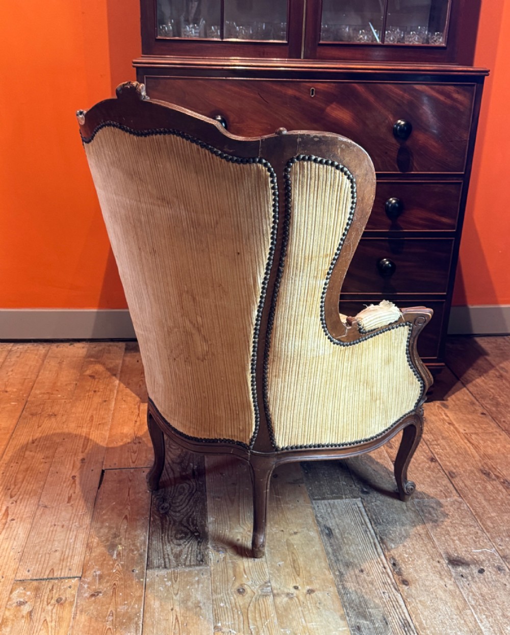 A Louis XV style bergere armchair featuring a carved dark wooden frame, enclosed upholstered arms, beige fabric, and cabriole legs. View V